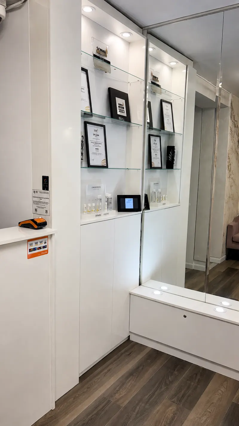 Zona de recepție cu vitrine albe și diplome expuse